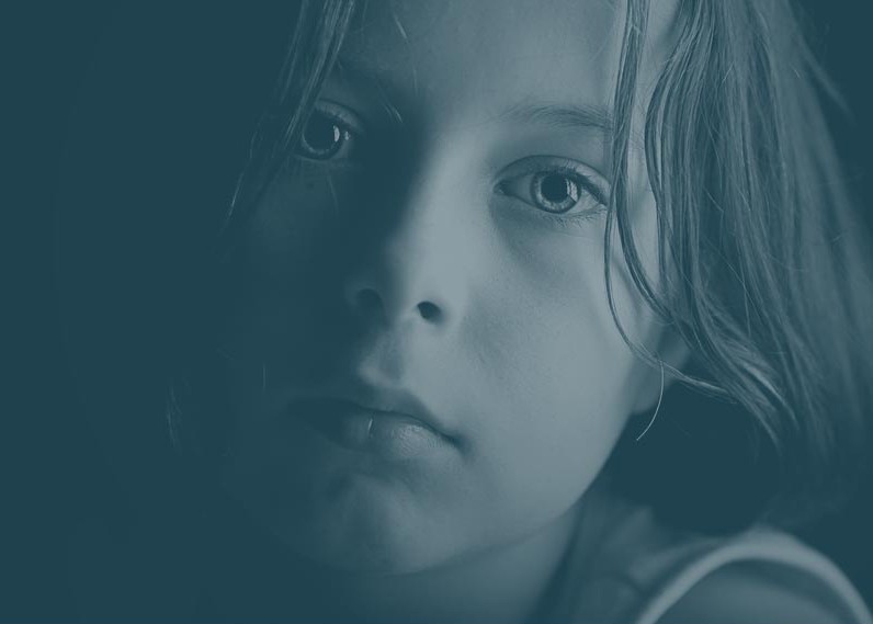 Close up photo of a child with a sad facial expression